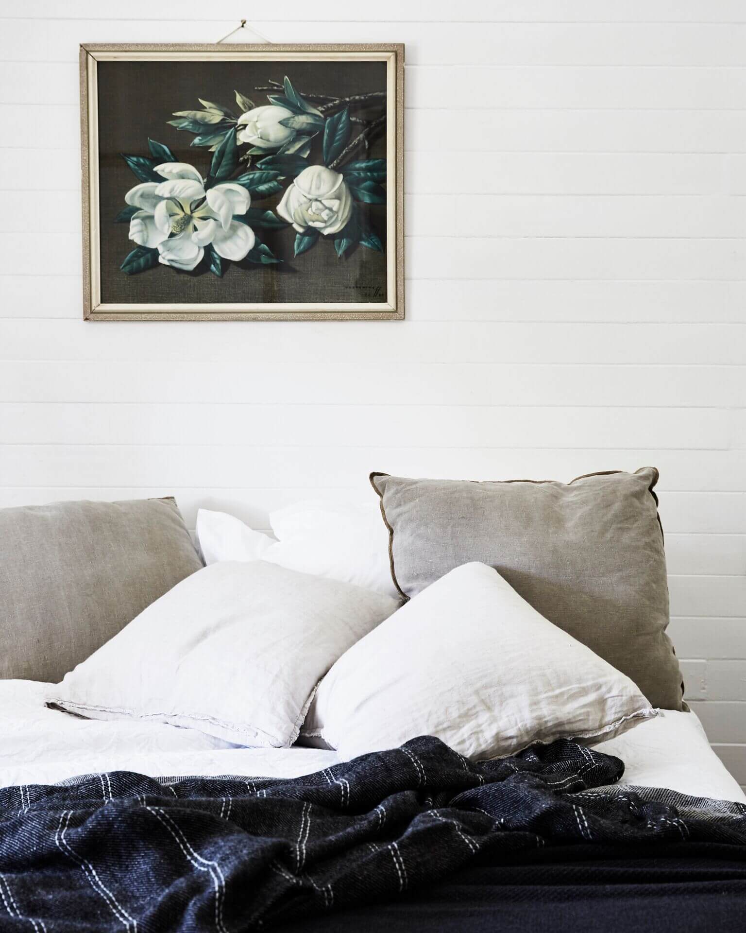 Bedroom at The Cottage, Byron Beach Abodes with vintage floral artwork, and a bed with layers of linen