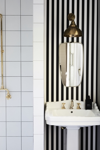 Ensuite with black and white striped wallpaper, brass tapware and wall light at The Bower Cottage, Byron Bay