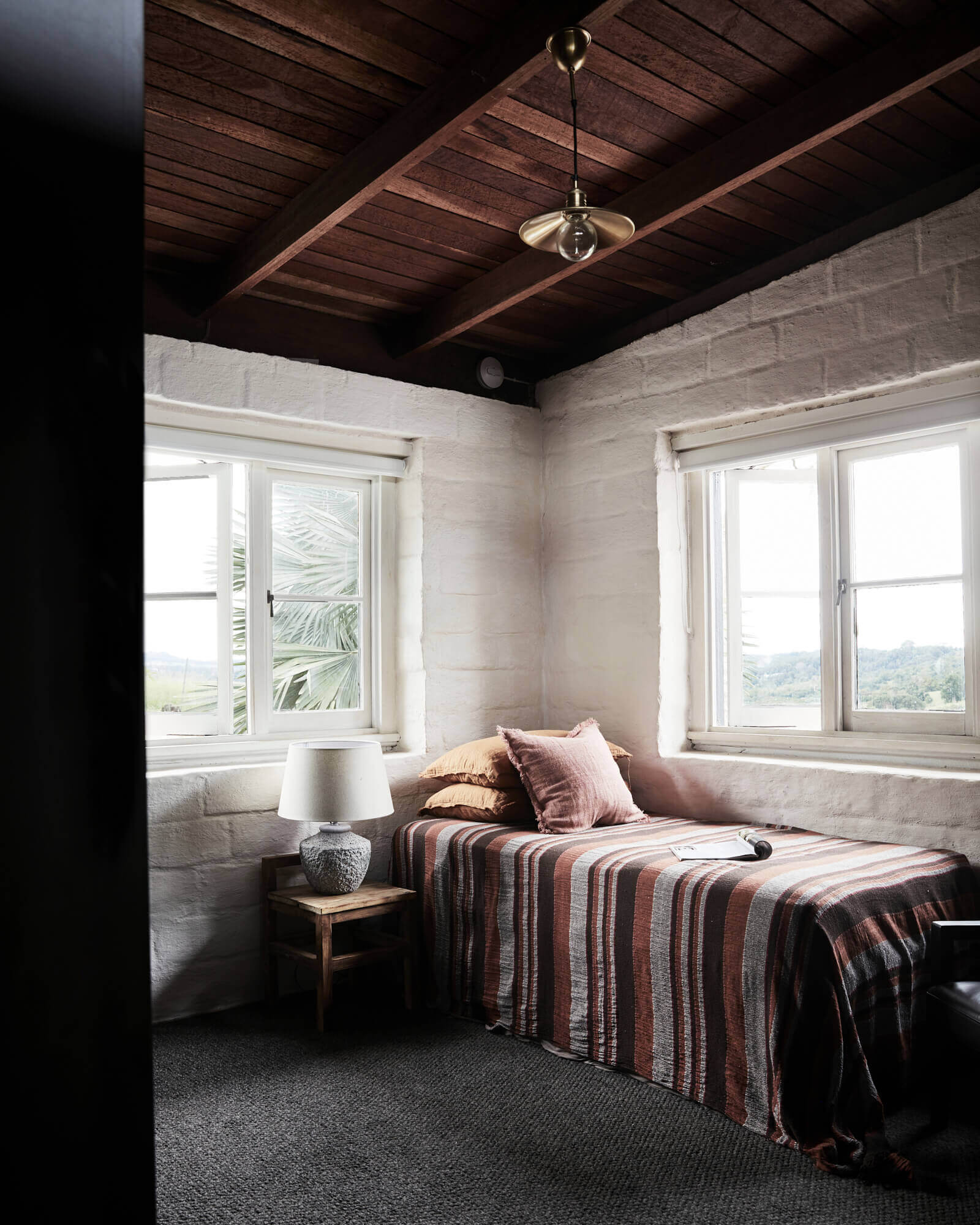 Single bedroom with mud-brick walls, timber ceiling and original windows at The Perch, Byron Beach Abodes