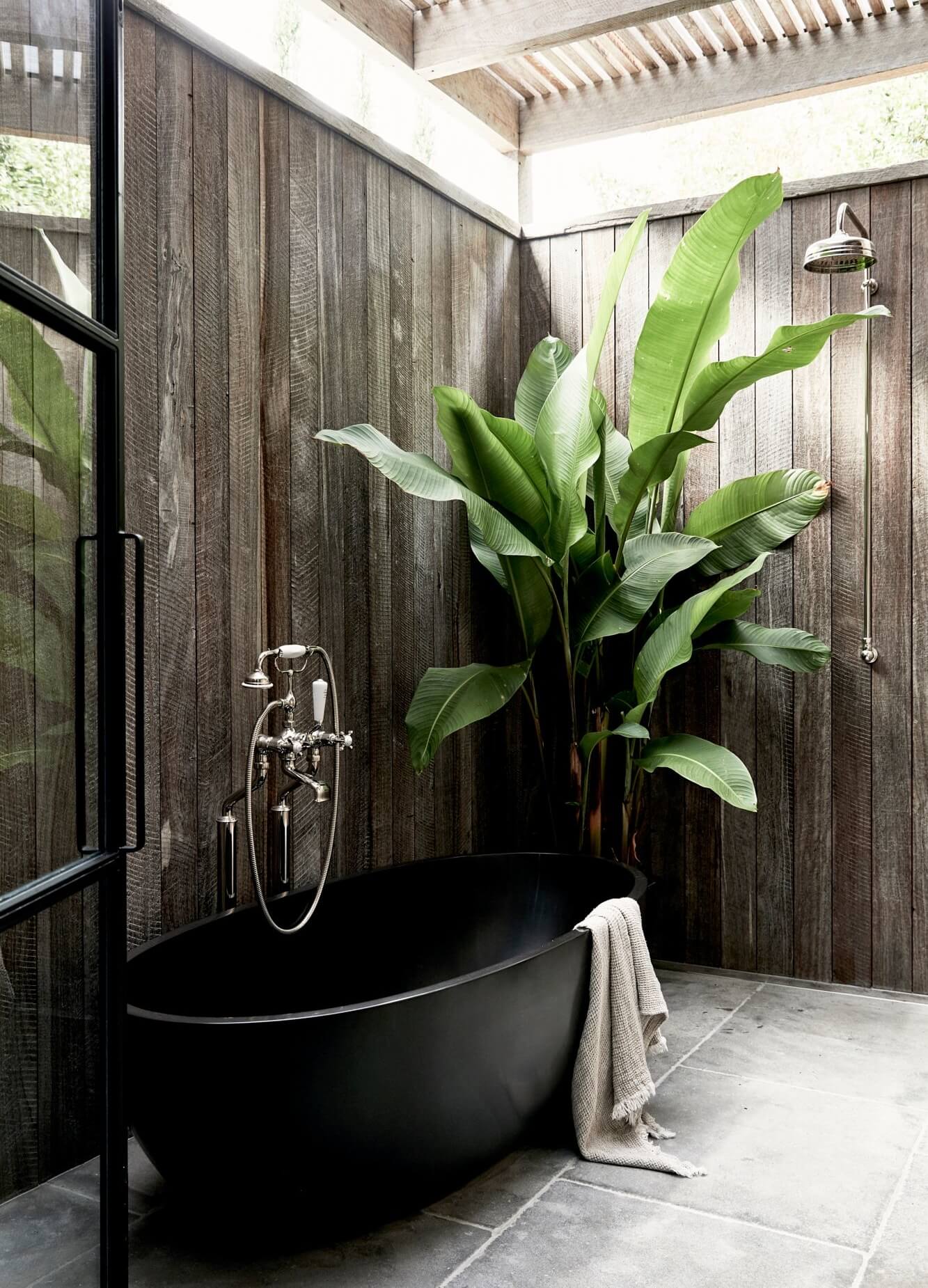 Ensuite at The Cabin, Byron Beach Abodes with black stone bathtub, tapware from English Tapware Company and huge indoor feature plant