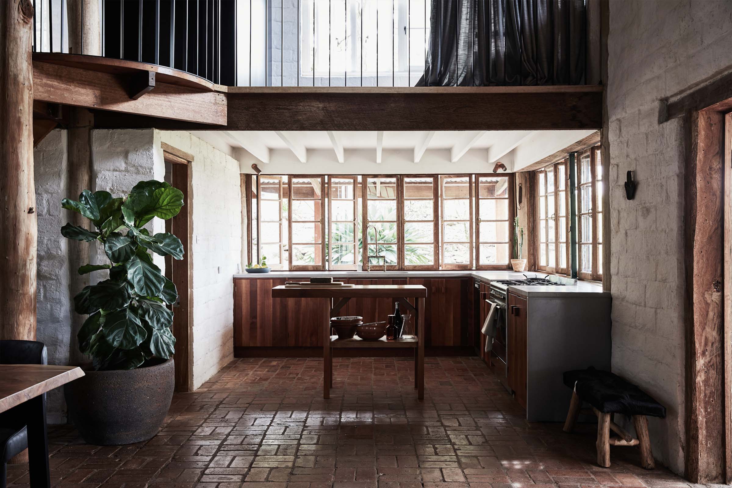 Rustic kitchen with dappled sunlight and natural brick-paved flooring at The Perch, Byron Beach Abodes