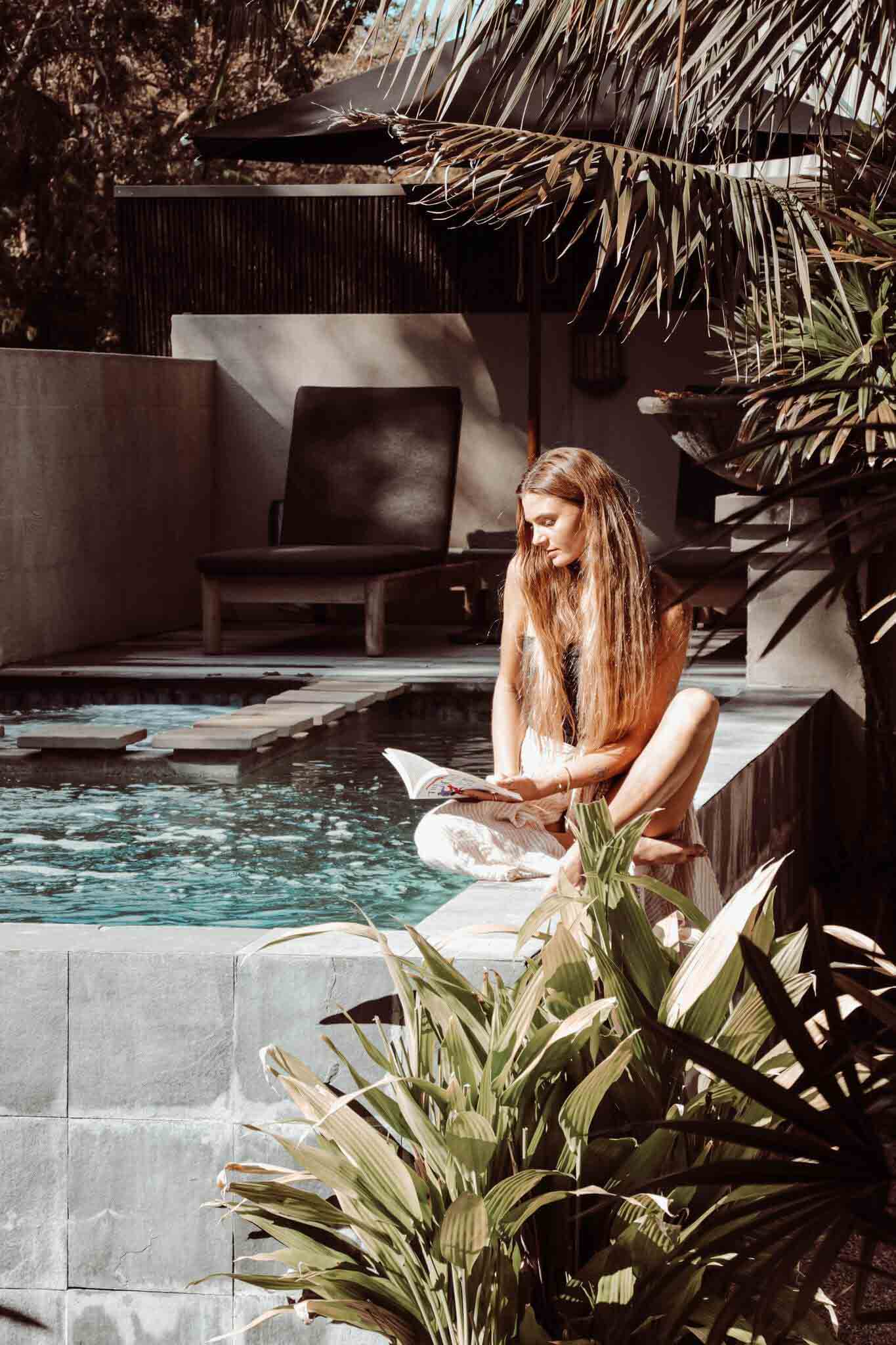 Sjana Elise reading poolside at The Villas of Byron