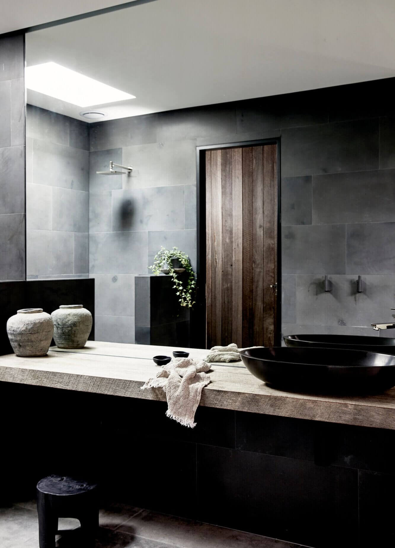 Ensuite at The Cabin, Byron Beach Abodes with dark wall tiles, double shower with skylight above, timber vanity and black feature vanity bowl