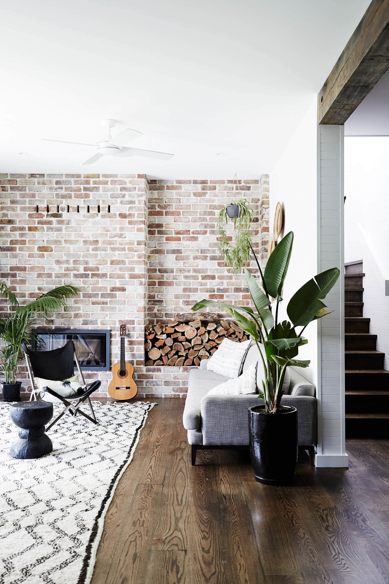 Lounge room at Magnolia House, Byron Beach Abodes with exposed brick wall, fireplace and textured rug and furnishings