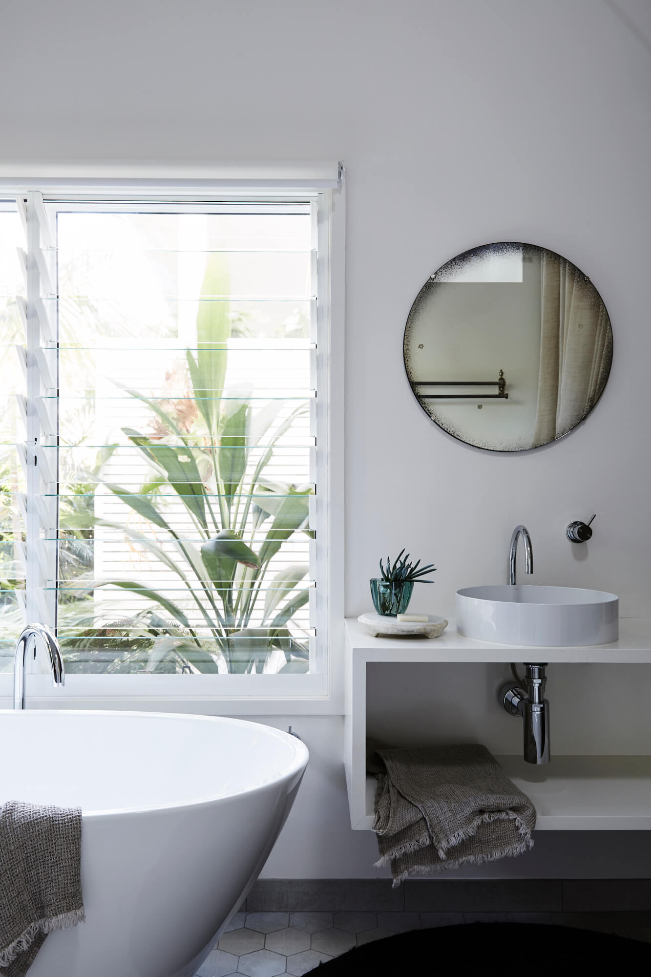Master ensuite at The Chalet, Byron Beach Abodes with bathtub, antique glass mirror and banks of louvre windows looking out to the tropical garden