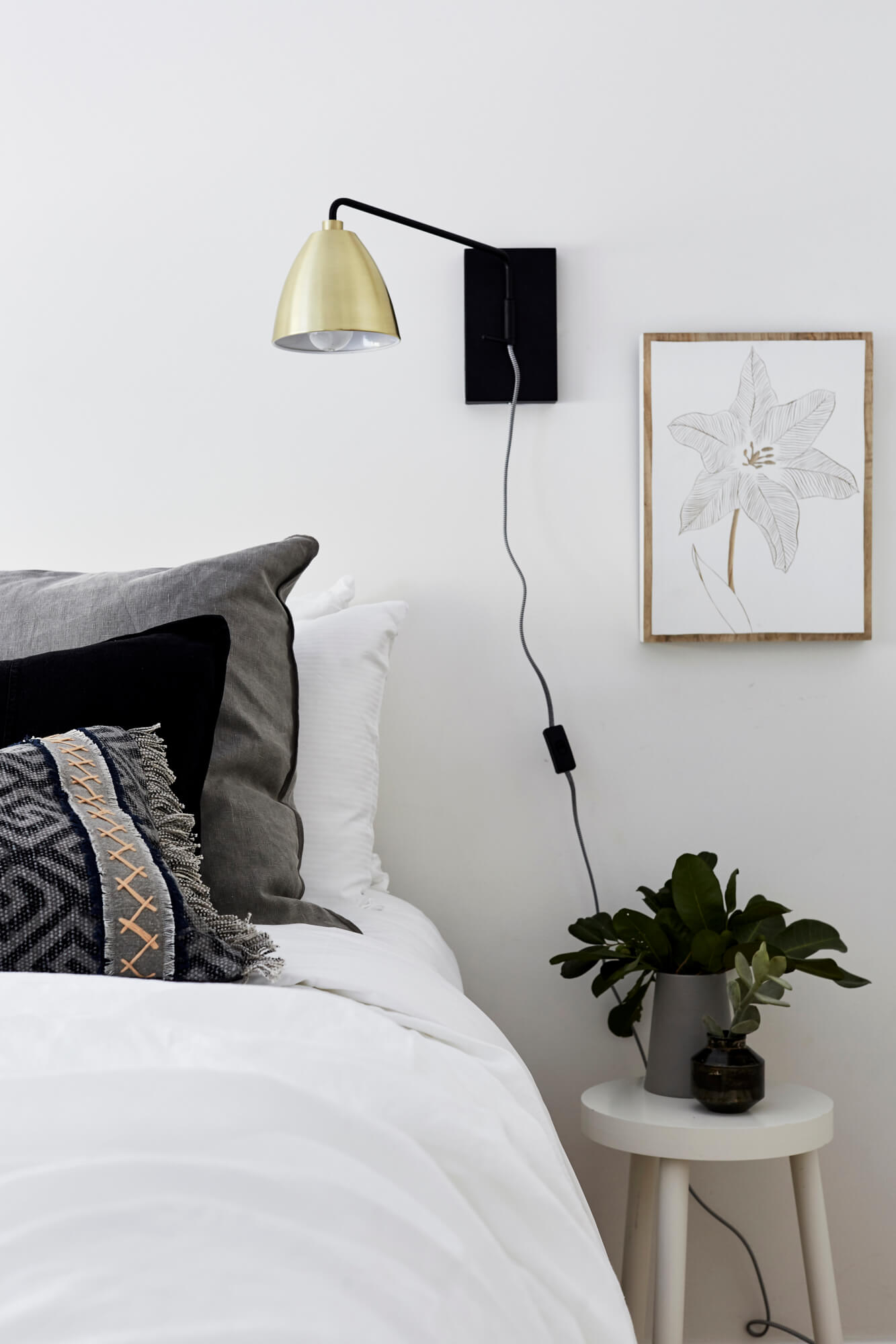 Bedrooms details at Bower House, The Bower Byron Bay with black and brass wall light, printed artwork and bed with linen and block printed cushions