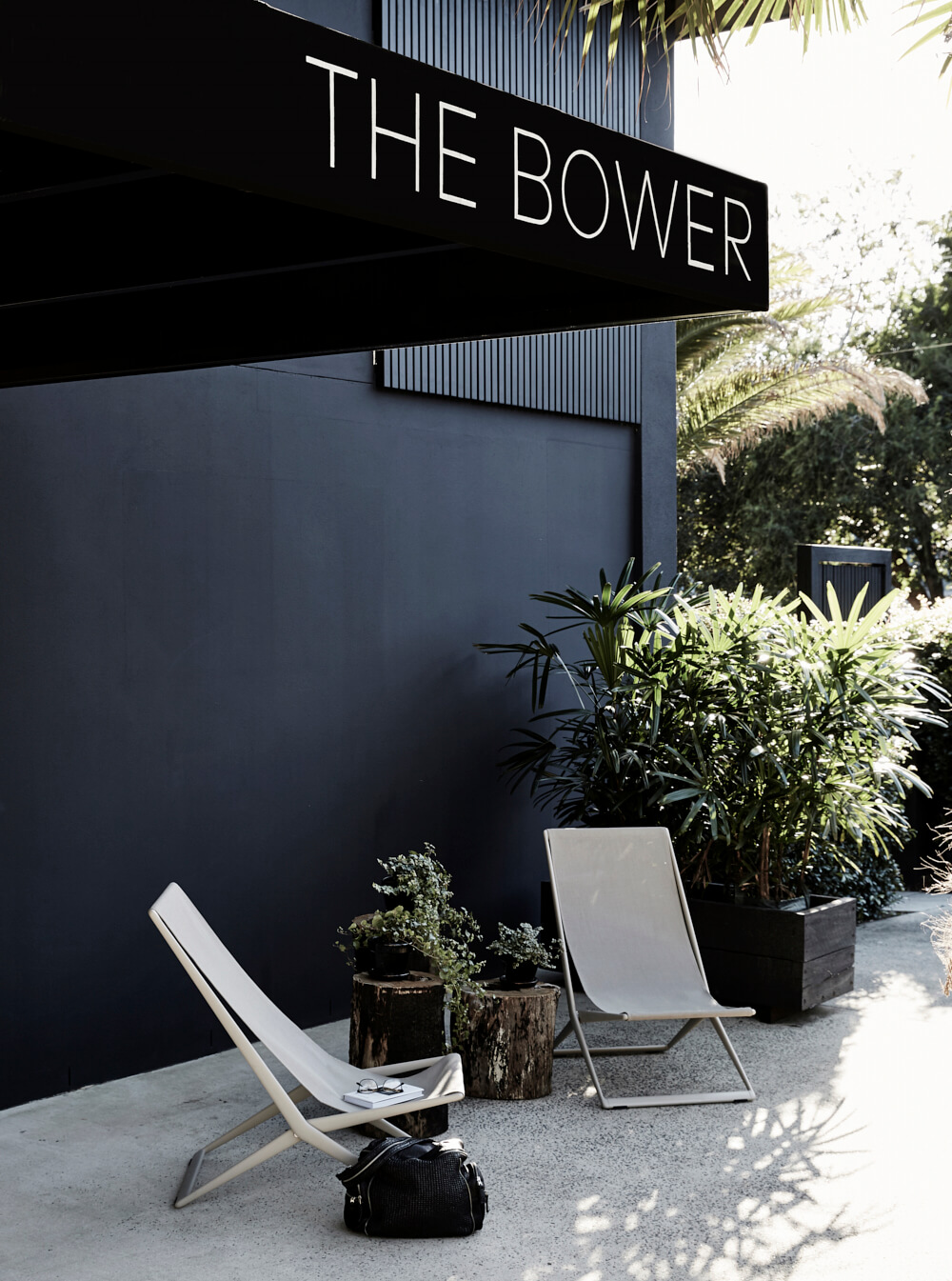 Entrance to The Bower Byron Bay with grey sling chairs and greenery