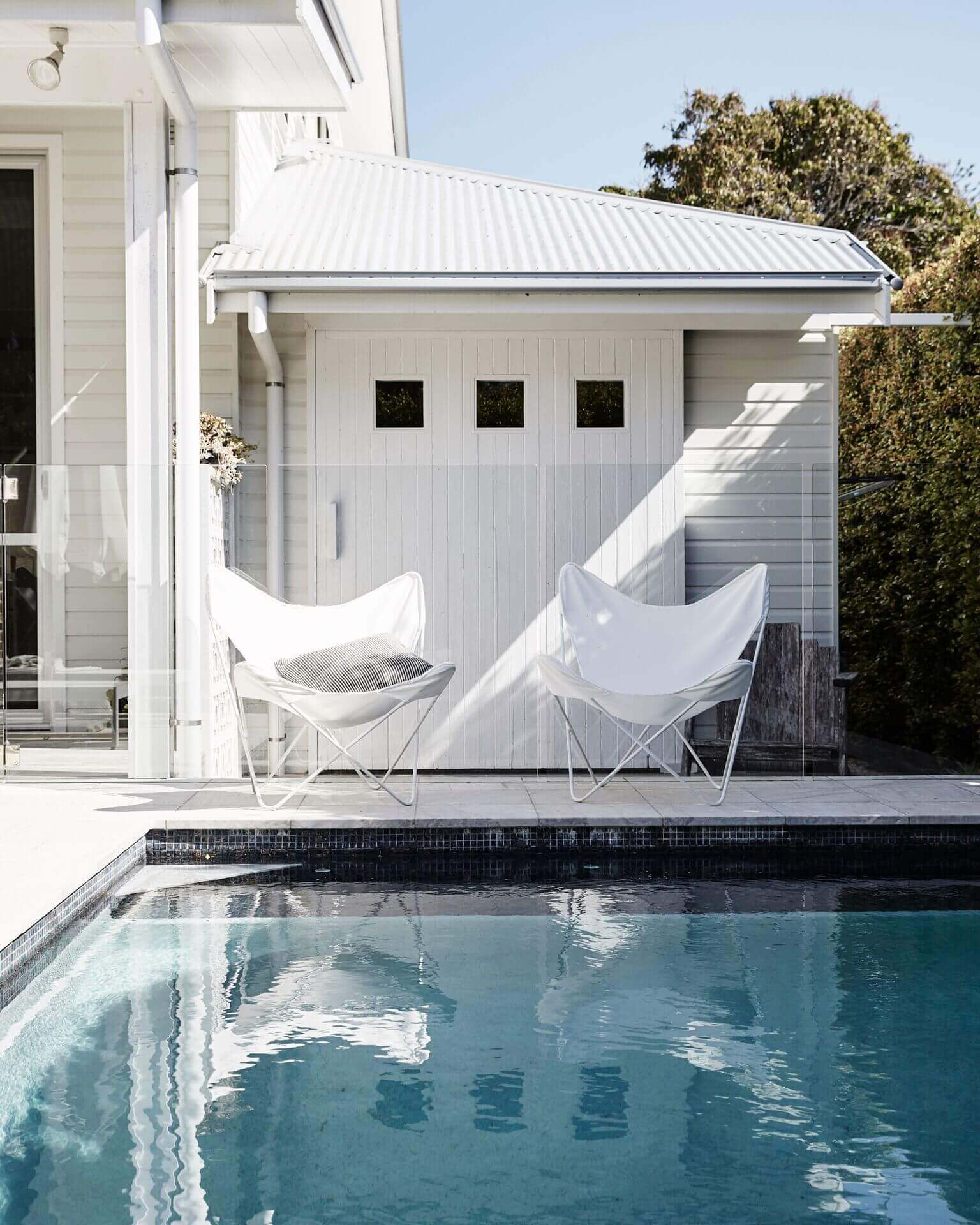 White butterfly chairs beside the pool at Magnolia House, Byron Beach Abodes