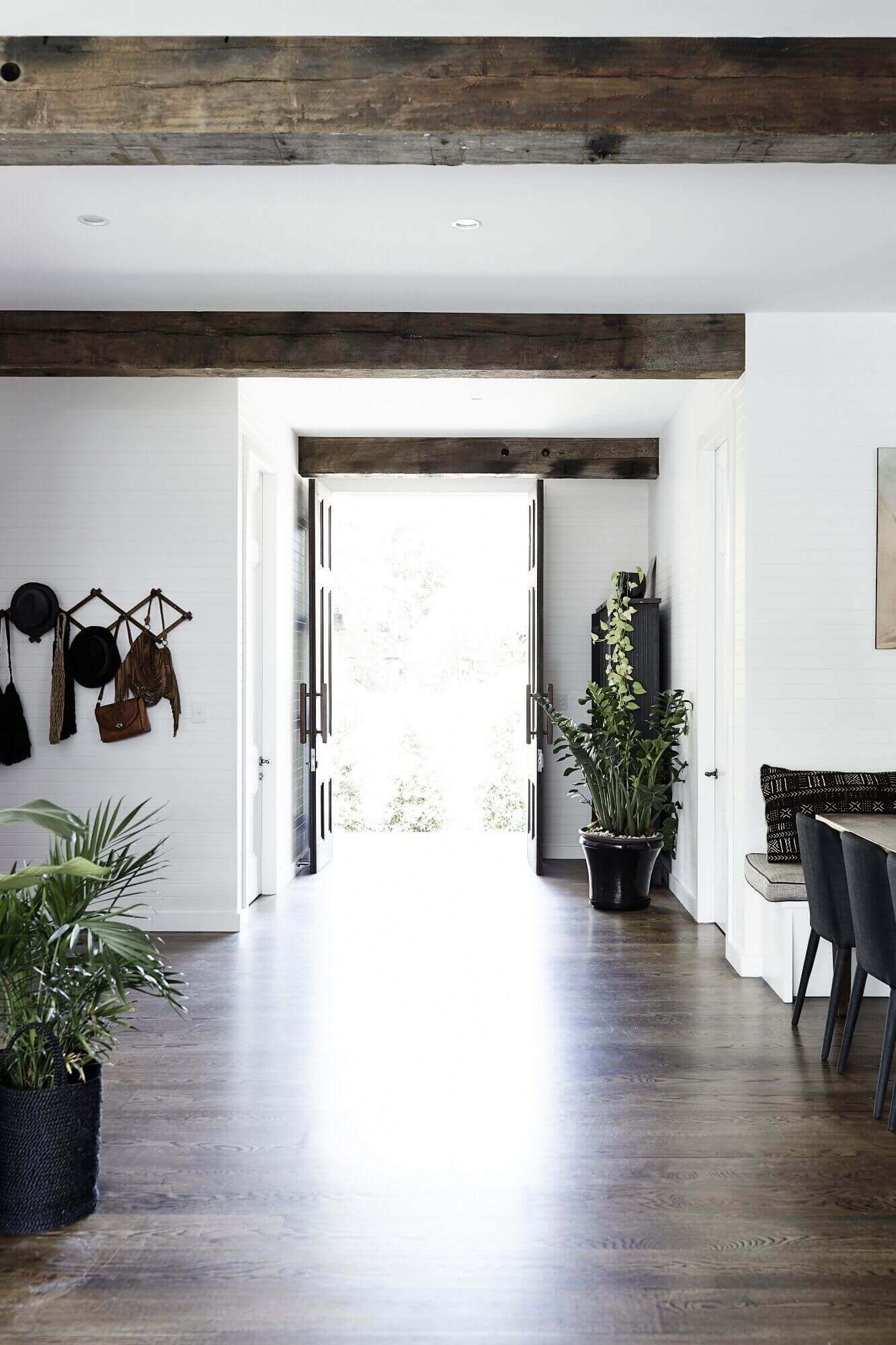 Entry and hallway at Magnolia House, Byron Beach Abodes with white timber panelled walls, antique timber door and recycled timber beams
